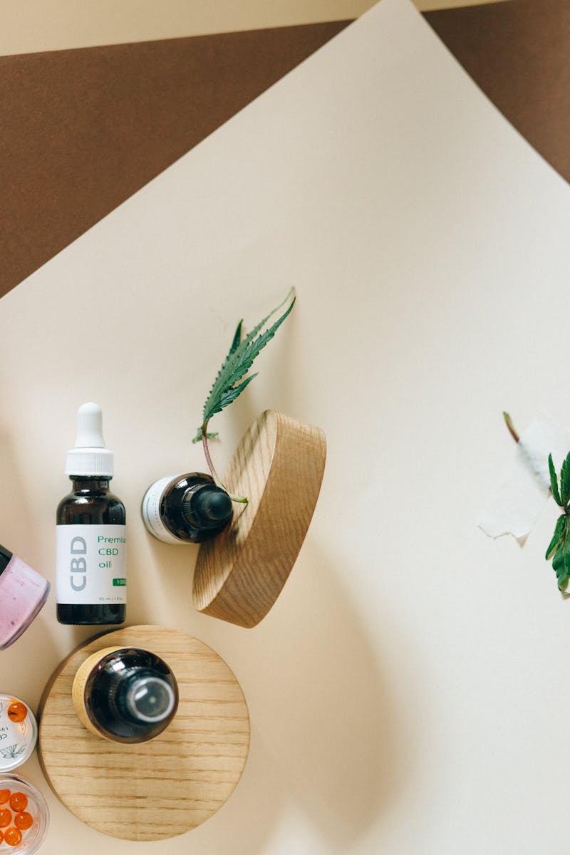 Stylish arrangement of CBD oil bottles with hemp leaves on a neutral backdrop, promoting natural wellness.